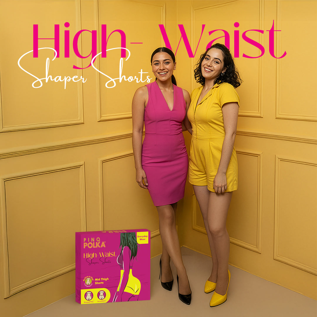 Two women standing next to each other with a 'High Waist Shaper Shorts' product box on a yellow paneled wall.
