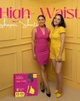 Two women standing next to each other with a 'High Waist Shaper Shorts' product box on a yellow paneled wall.